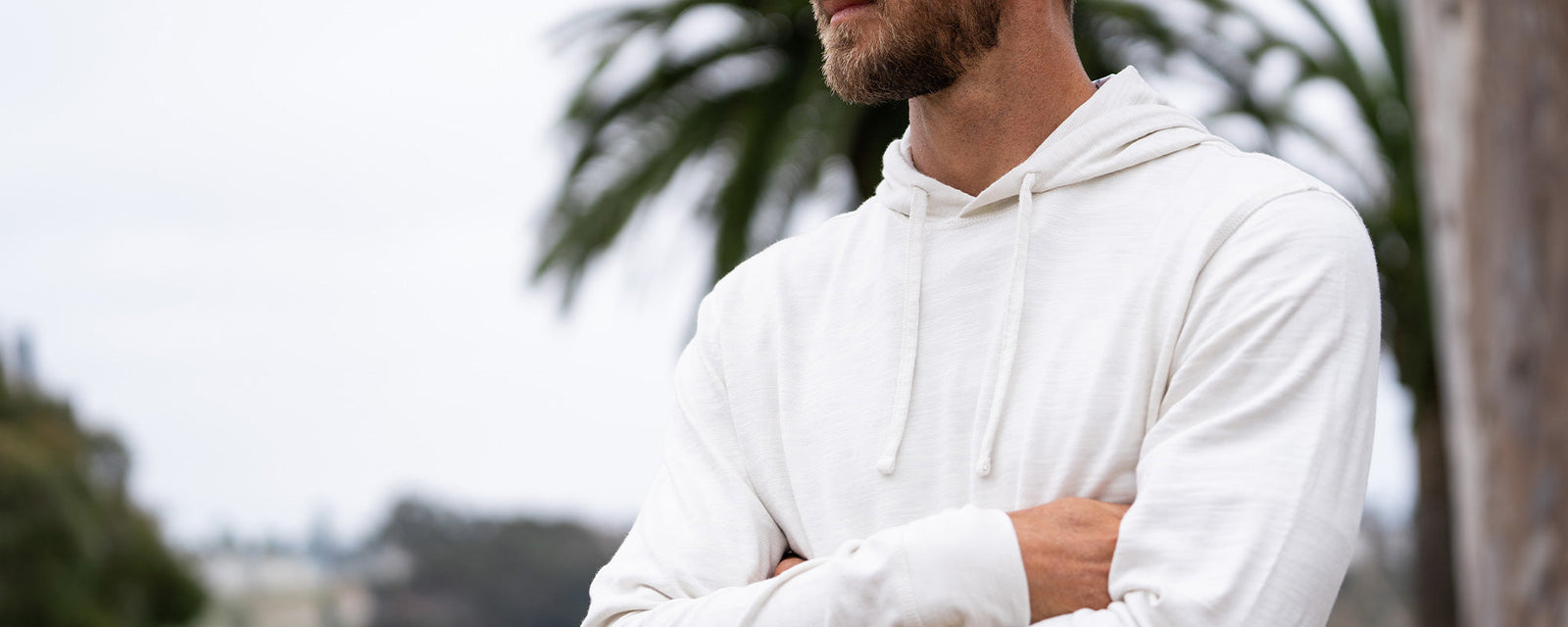 Guy walking with surf board wearing a stripe crew layer
