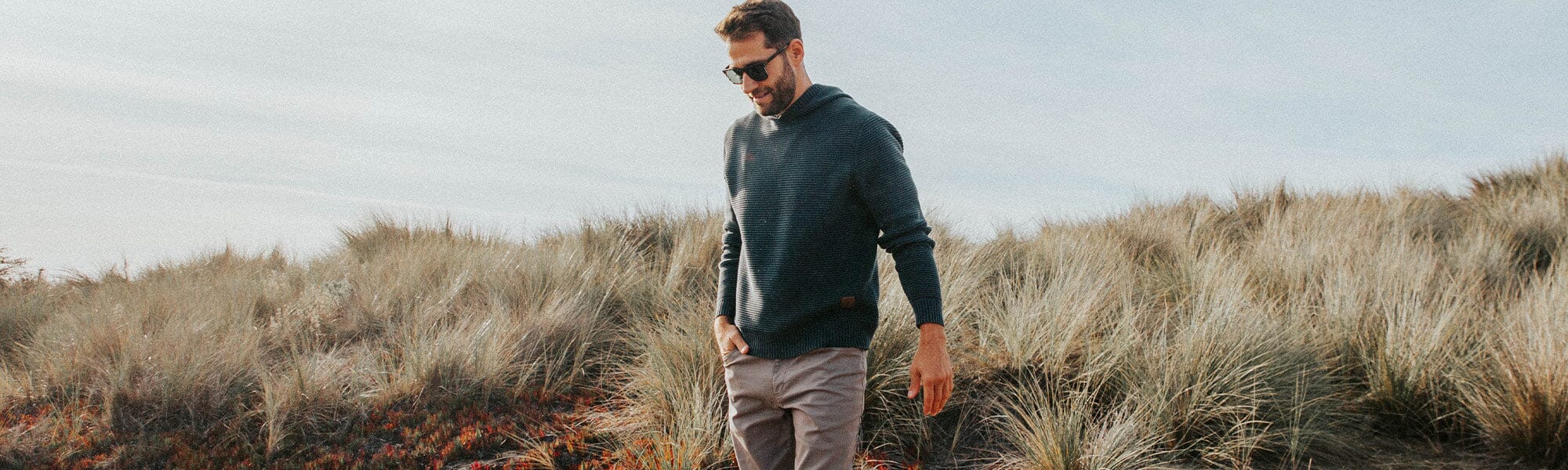 Guy walking with surf board wearing a stripe crew layer